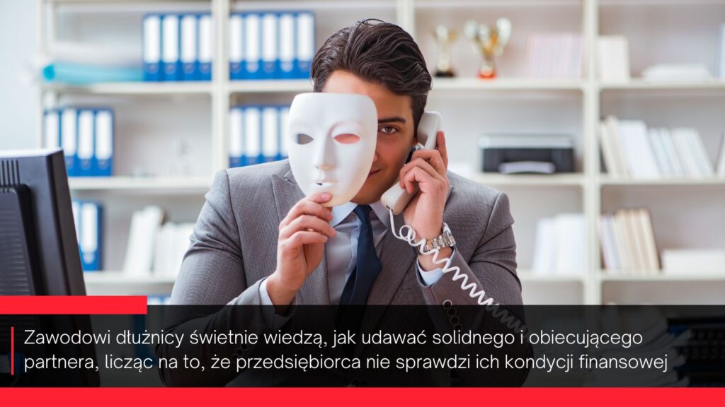 Zdjęcie elegancko ubranego mężczyzny siedzącego za biurkiem i wjednej ręce trzymającego słuchawkę telefonu, a w drugiej białą maskę, którą częściowo zakrywa twarz.