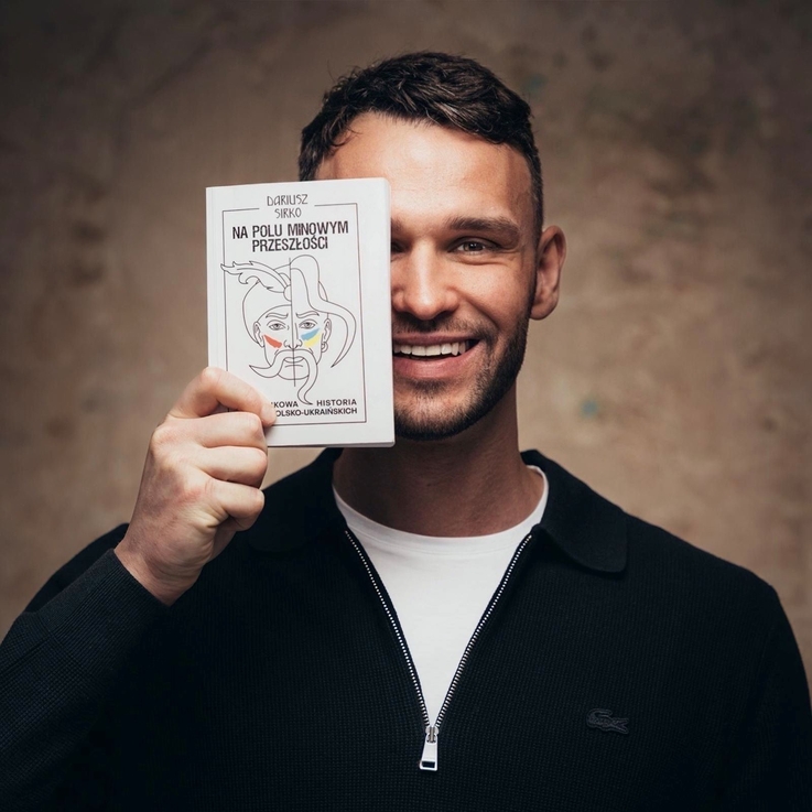 Zdjęcie autora Dariusza Sirko oraz trzymanej przez niego książki pt. „Na polu minowym przeszłości”.