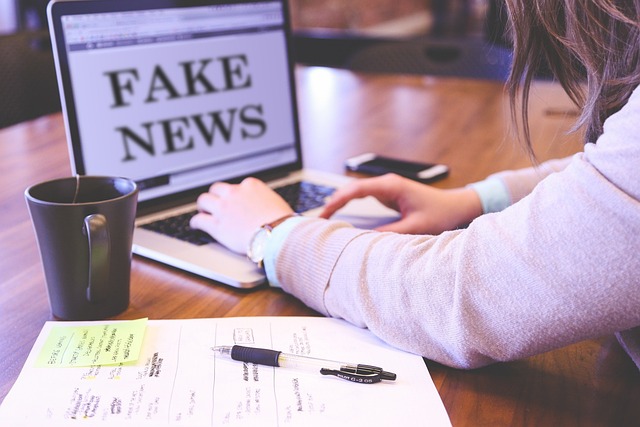 Pisanie na laptopie z napisem na monitorze FAKE NEWS